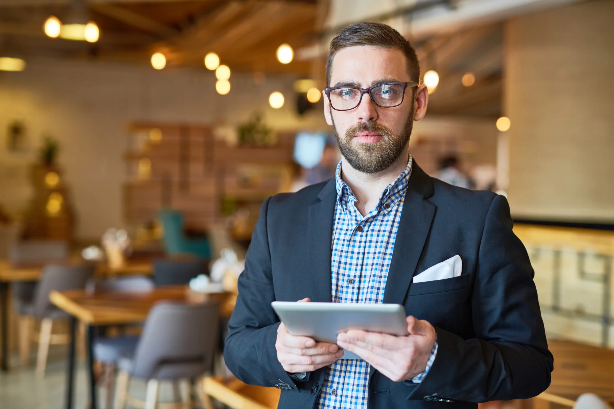 Man in blazer with tablet in modern café